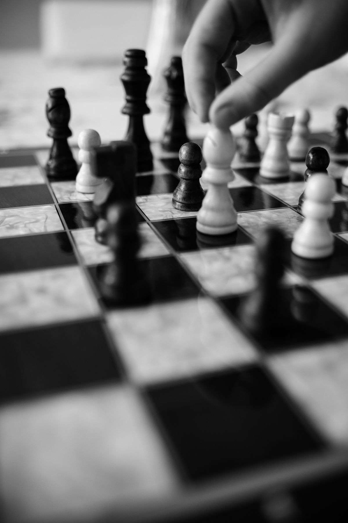 Hand moving chess piece in a monochrome image representing Black opening strategy